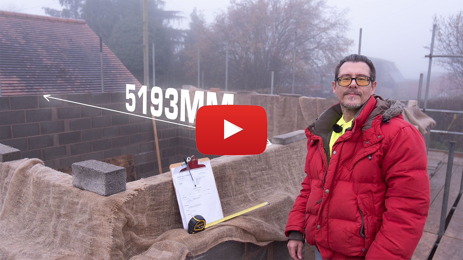 Person in a red jacket standing next to a construction site with a YouTube play button overlay.