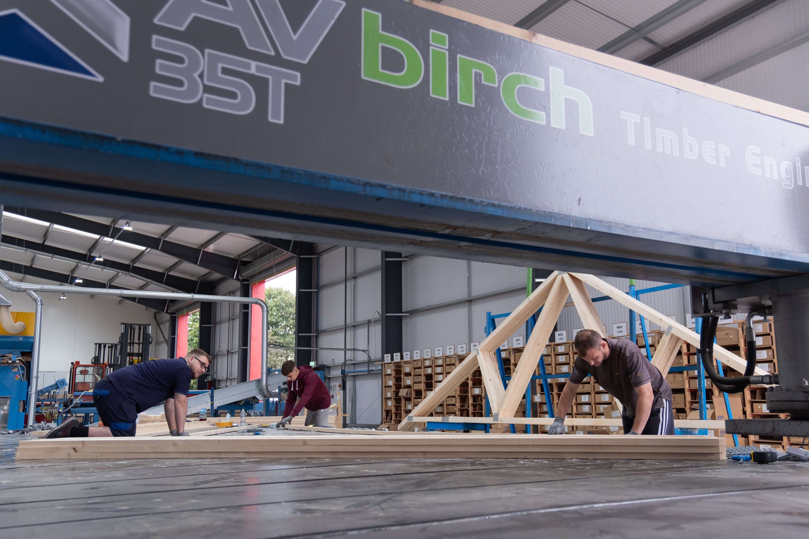 men making a roof truss in a factory