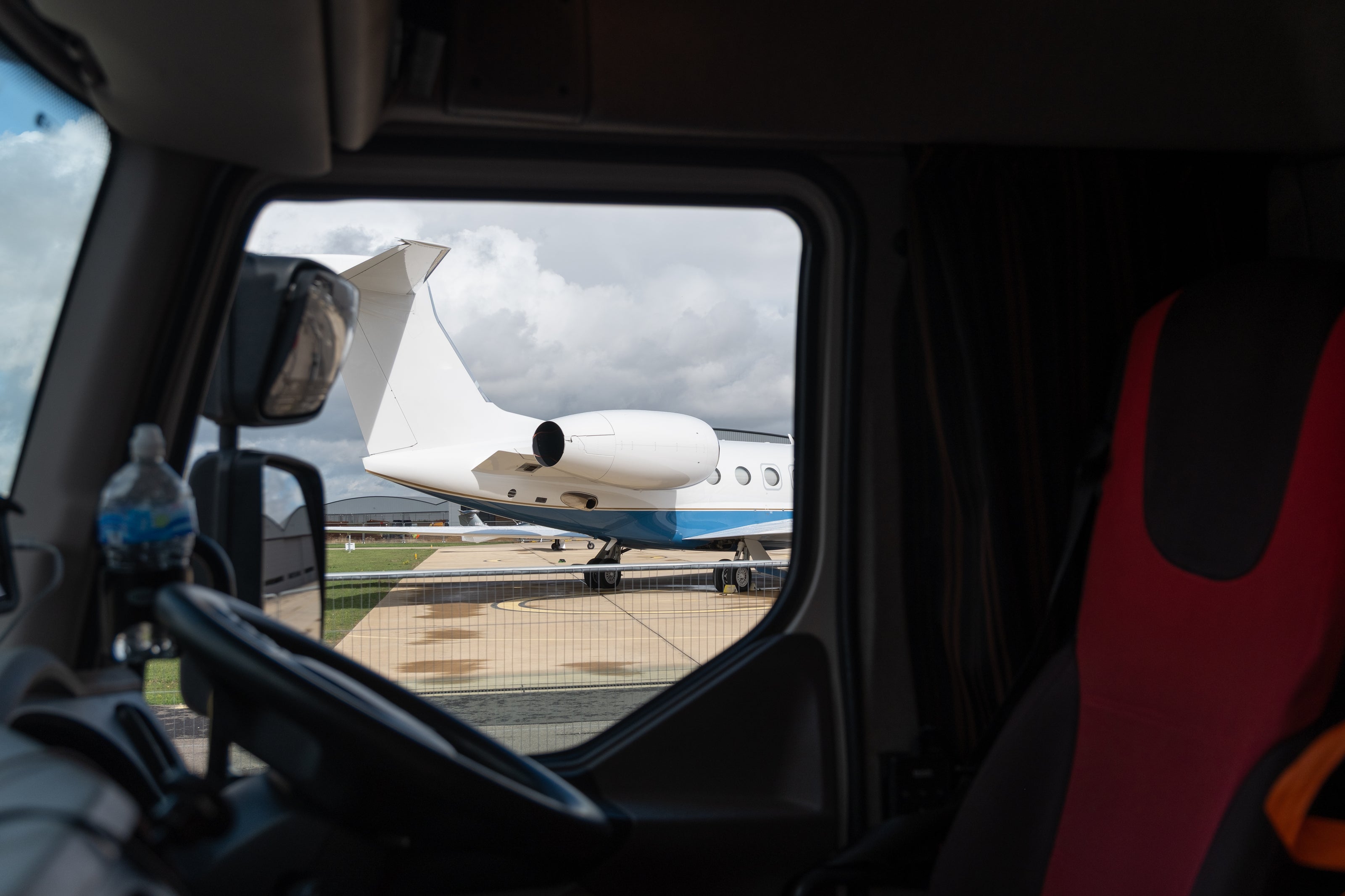 a view of a private jet from inside the cab of a lorry