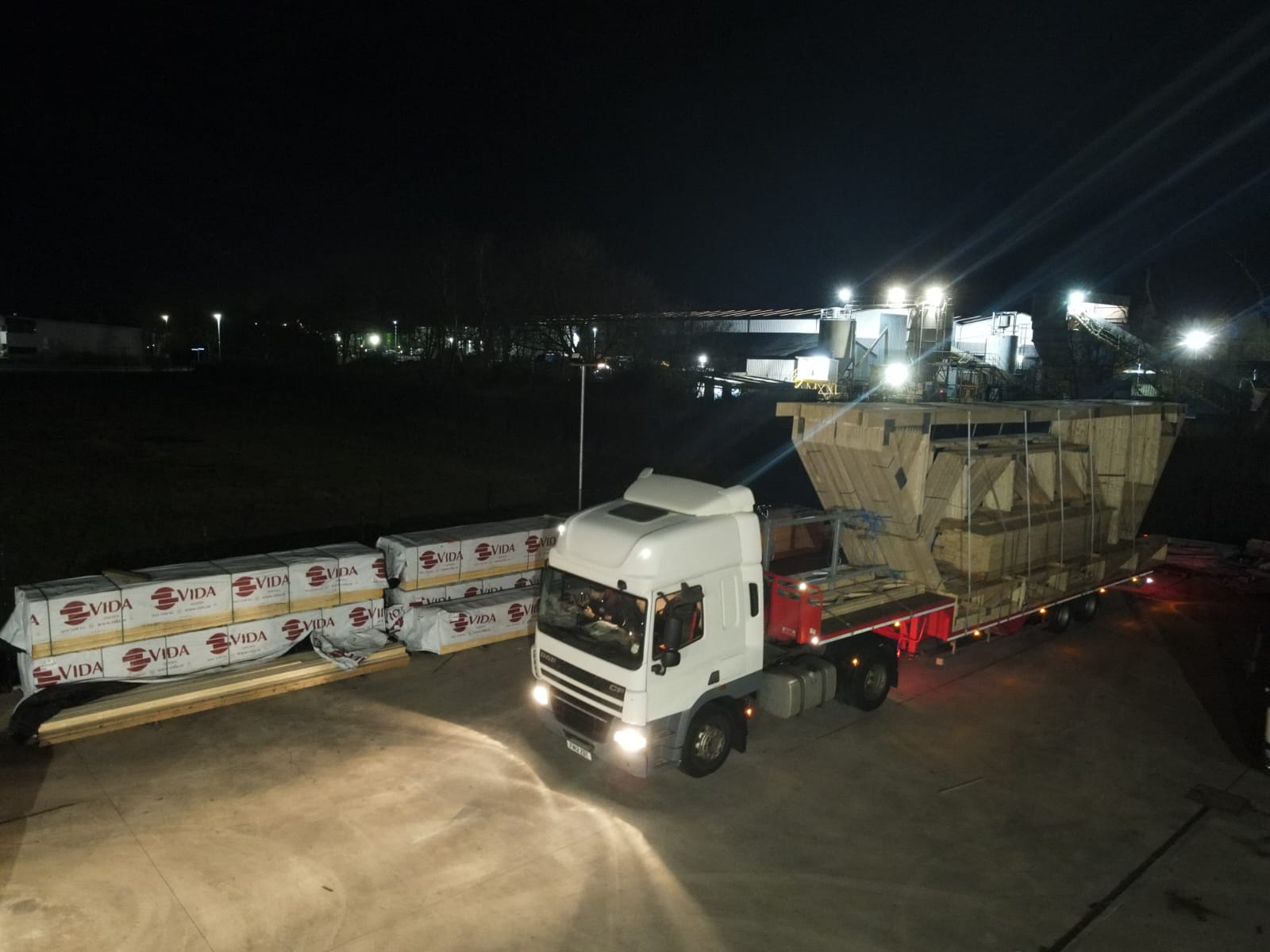 a lorry in a yard with roof trusses on the back