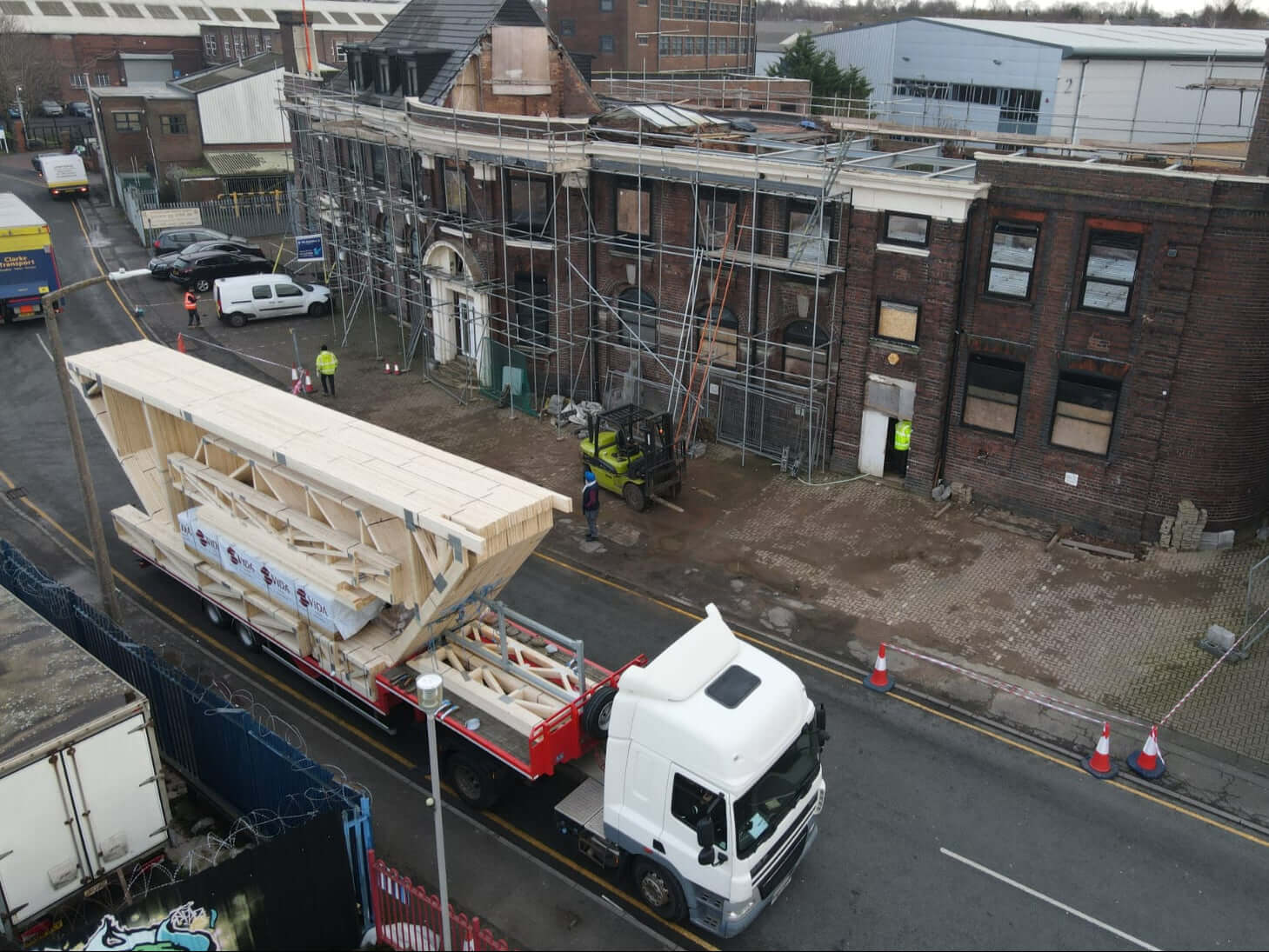 White lorry with large attic trusses on the bed delivering to a building in birmingham, england