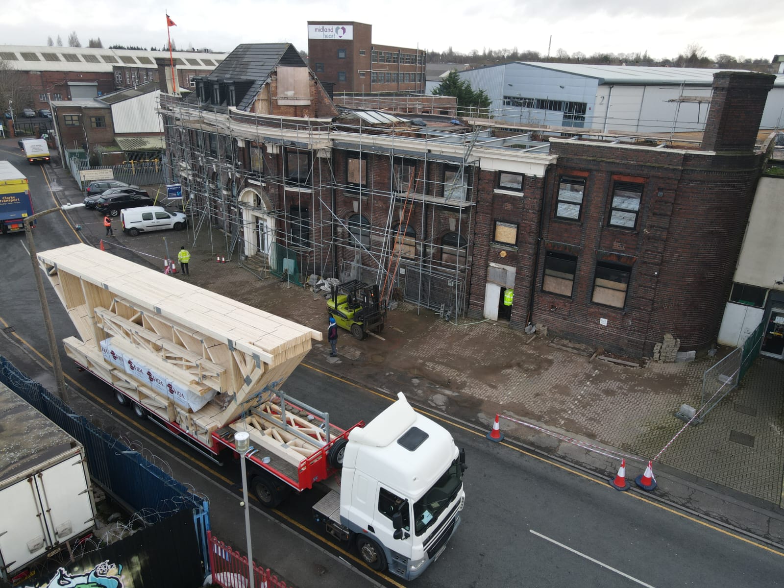 attic trusses on the back of a lorry with a large building behind