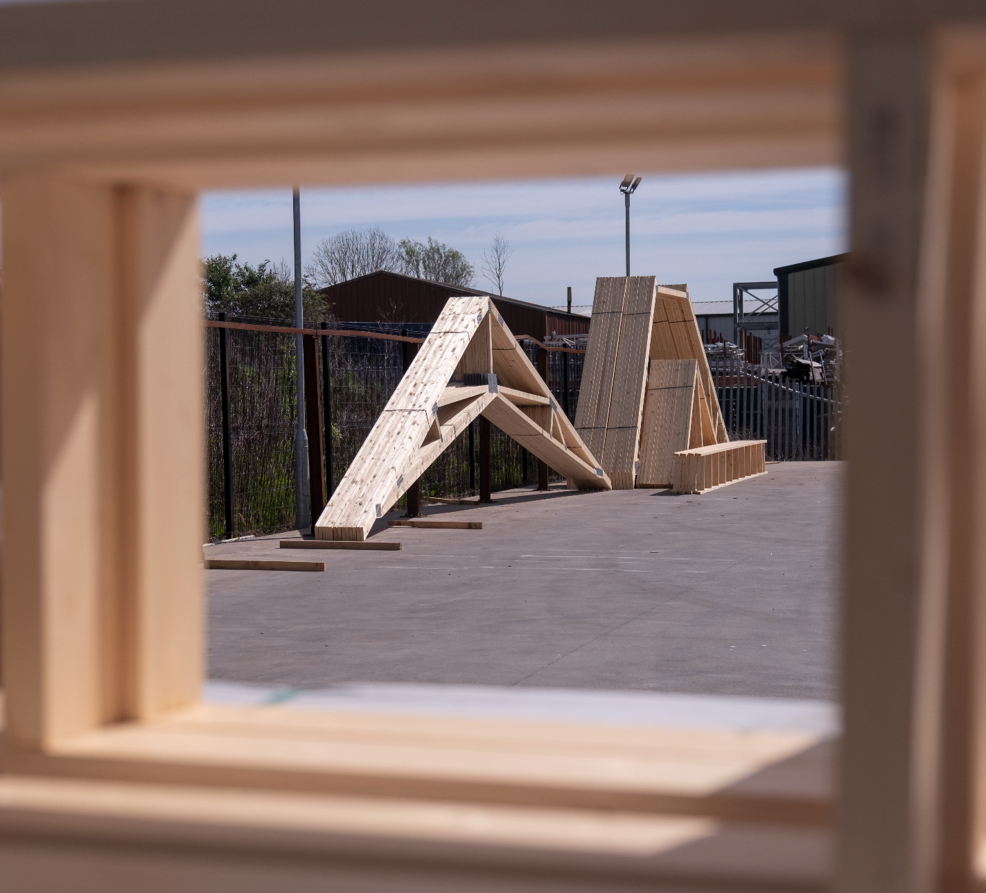 scissor trusses leant up against a fence in a yard