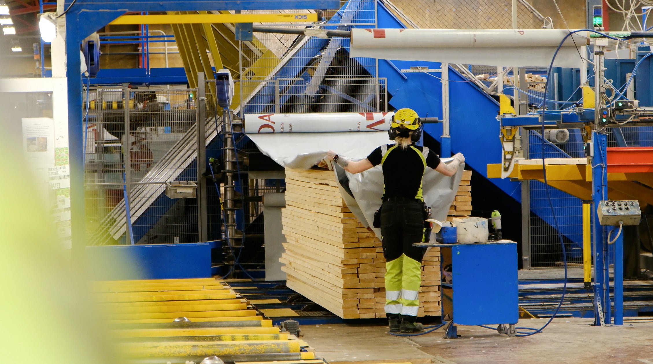 Worker wrapping packs of timber in a factory in sweden.