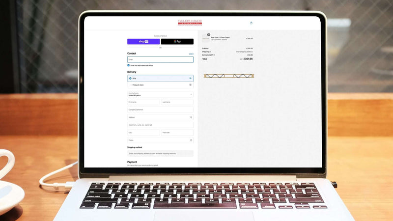 a laptop on a wooden table with the tailor made designs website up