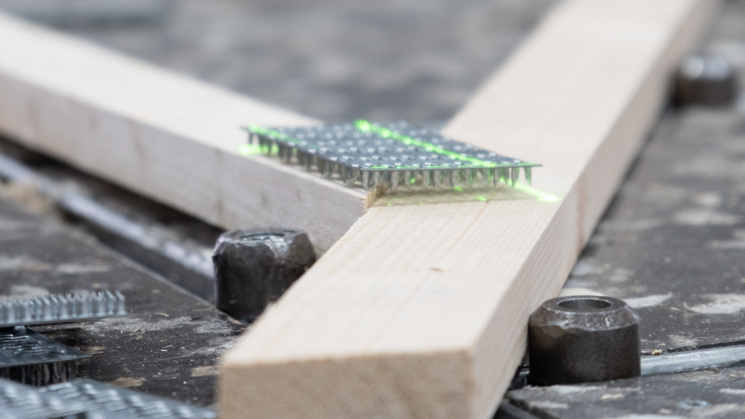 a close up of a timber roof truss with a green laser shining down on the nailplate