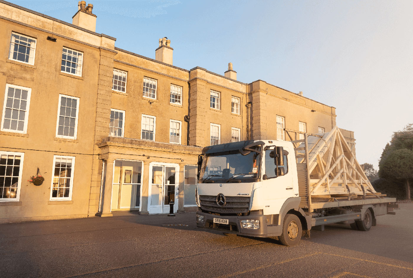 roof trusses on a flatbed lorry in staffordshire with a large georgian stately home behind