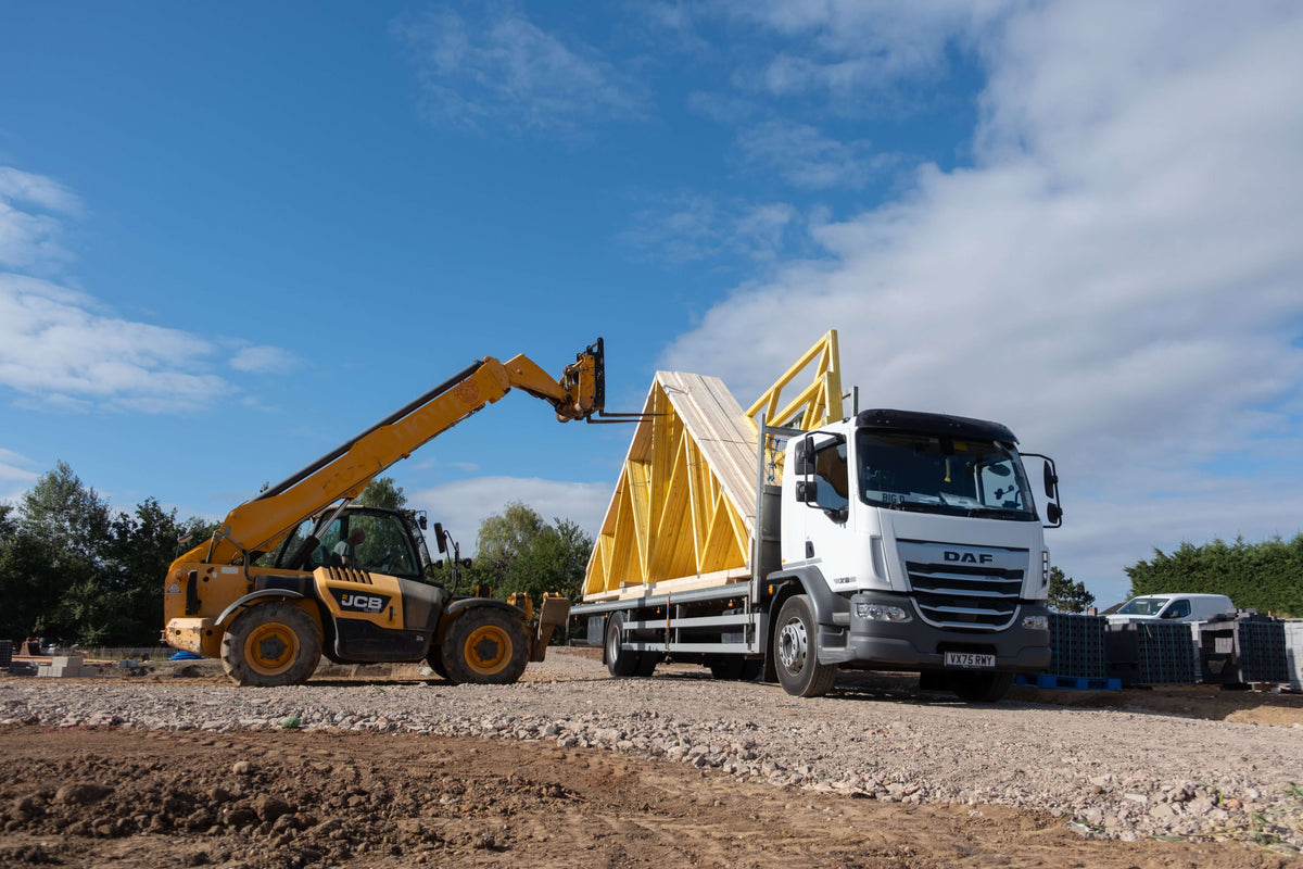 a yellow jcb unloads fink trusses from the back of a flatbed lorry in worcestershire 